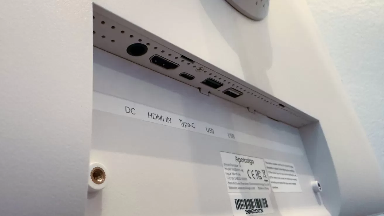 Back of a monitor showing recessed ports labeled DC, HDMI in, Type-C, and USB, with screws, ventilation holes, and a product information sticker on the lower panel