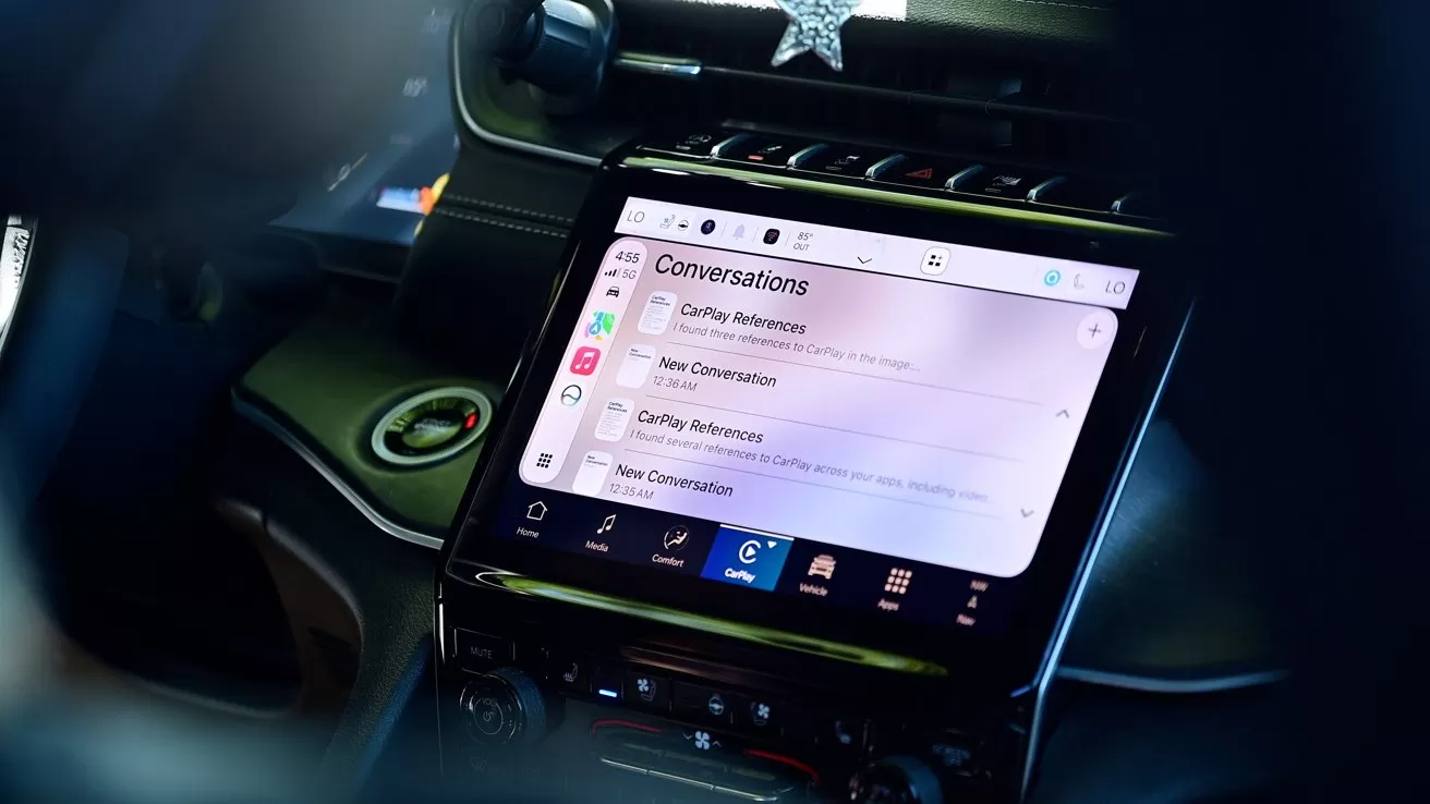 Car dashboard featuring a large central touchscreen displaying a messaging app conversation list, with unread messages, various app icons below, and surrounding car controls and steering wheel visible