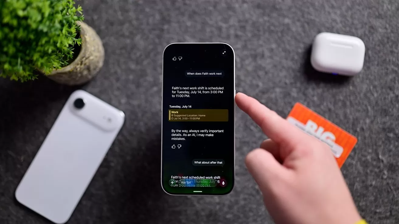 Hand holding a smartphone displaying a dark-themed notes app on a gray surface, with a white phone, wireless earbuds case, plant, and orange card nearby