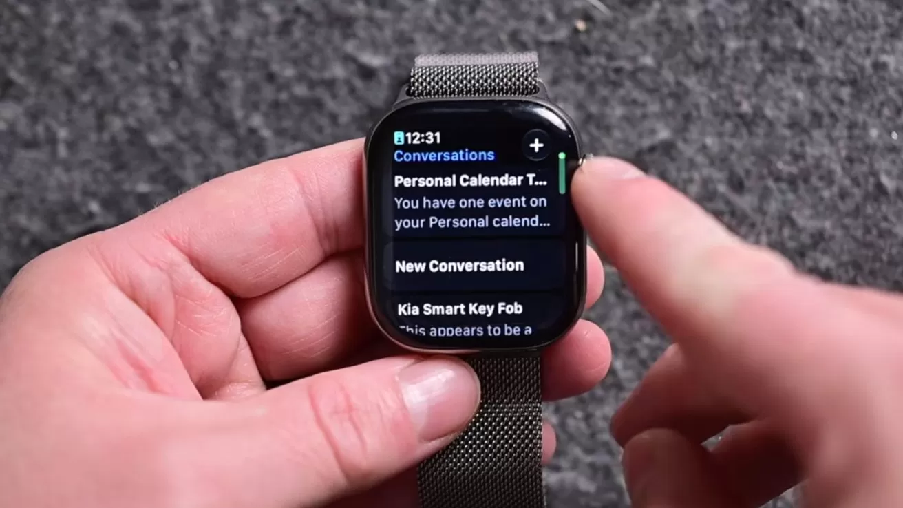 Close-up of hands operating a smartwatch with a metal mesh band, displaying a notifications list including personal calendar events and smart key fob alerts against a gray textured background